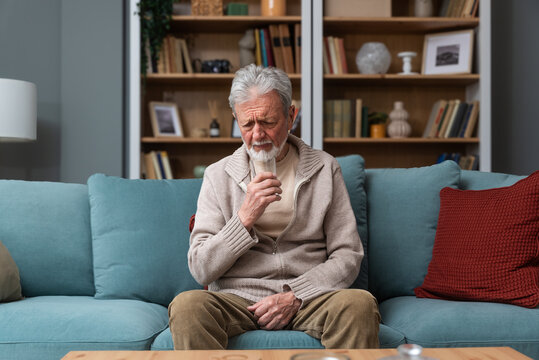 Senior man, widower or divorced, feeling sad, worry, abandoned and depressed, sitting alone at home, crying. Loneliness and sadness of older male with white hair and beard.