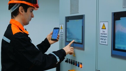 Operator uses control panel and smartphone to interact with industrial equipment supported by...
