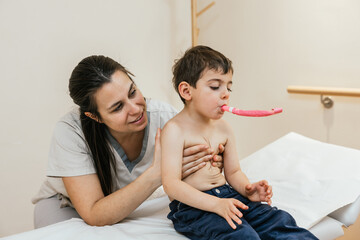 Physiotherapist assisting young boy with respiratory physiotherapy using pink device