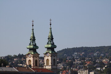 Two ornate church towers rise against a clear sky, showcasing the architectural beauty of a historic cityscape at midday