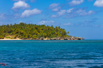 A serene coastal scene showcases a turquoise sea gently lapping against a rugged cliff topped with...