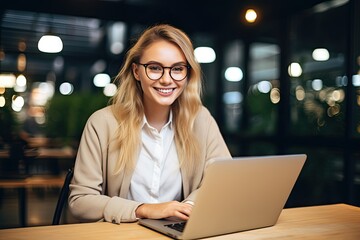 Young beautiful joyful woman smiling while working with laptop in office.