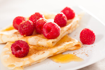 Delicious pancakes with fresh raspberries and honey