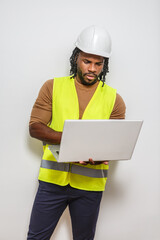 Construction worker wearing safety gear checks plans on a laptop in a studio setting