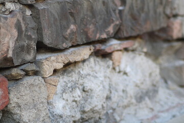 Textured wall made of various stones with a mix of colors showing weathering and age throughout afternoon light