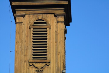A wooden structure with slatted ventilation perched against a clear blue sky in a serene setting...