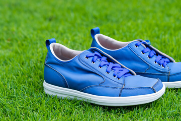 Man in blue and green sneakers is on lawn. grass summer nature concept. w in fashionable sneakers stands on a green lawn. a w in a green and white sneakers stands on a fashion lawn in stylish.