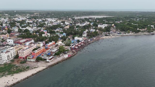 This aerial video showcase the serene atmosphere within the temple, with devotees offering prayers and performing rituals. the sacred Agni Theertham location Ramanathaswamy Temple in Rameshwaram