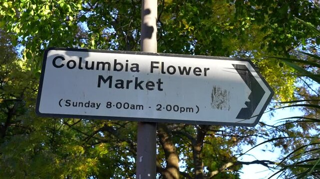 Columbia Road Flower Market sign in London pointing towards the market's Sunday opening hours