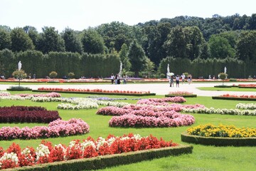 Colorful flowerbeds bloom in a lush garden as visitors stroll through the landscaped paths on a sunny day