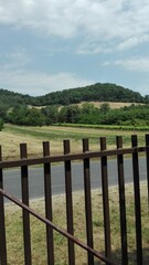 Scenic view of rolling hills and vineyards from behind a fence in daytime under a clear sky