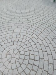 Patterned cobblestone pathway featuring a circular design during daylight in an urban environment