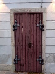 Old wooden door with decorative metal hardware in a historic building in a quaint European town at dusk