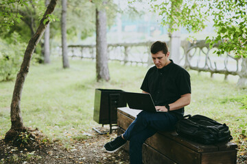 Fototapeta premium Portrait of young freelance programmer man working with laptop in forest park, software developer, IT technologies