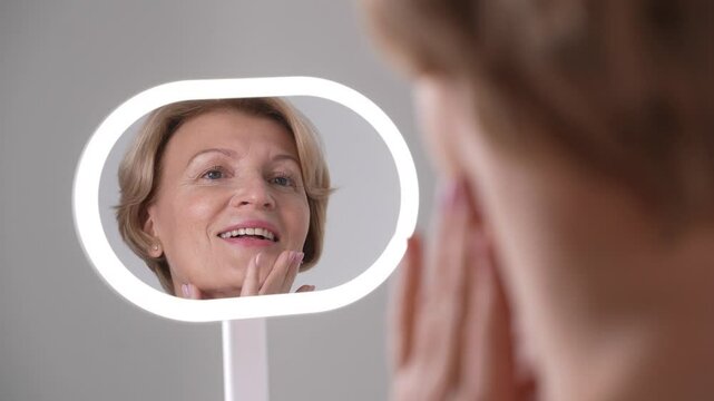 A mature woman gazes lovingly at her skin. Beautiful female aging with grace, dignity, and selfcare practices. Skincare and aging