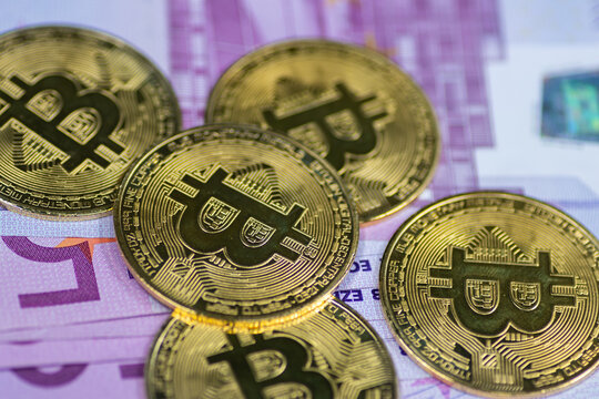Golden Bitcoin coins, arranged alongside a pile of Euro notes, symbolizing the interplay between traditional and digital currency in modern finance