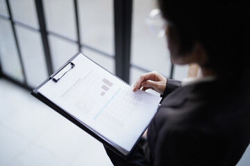 Asian businesswoman in suit standing reading documents
