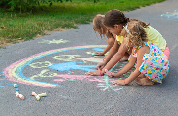 Children draw with chalk on the asphalt. Selective focus.