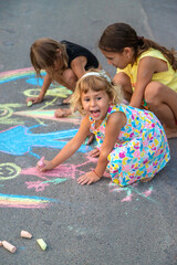 Children draw with chalk on the asphalt. Selective focus.