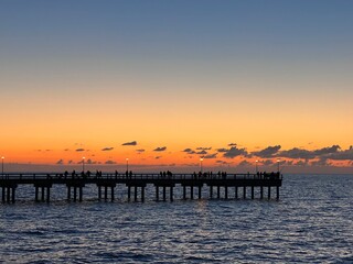 Obraz premium Palanga pier bridge with people resting against the background of the sea sunset