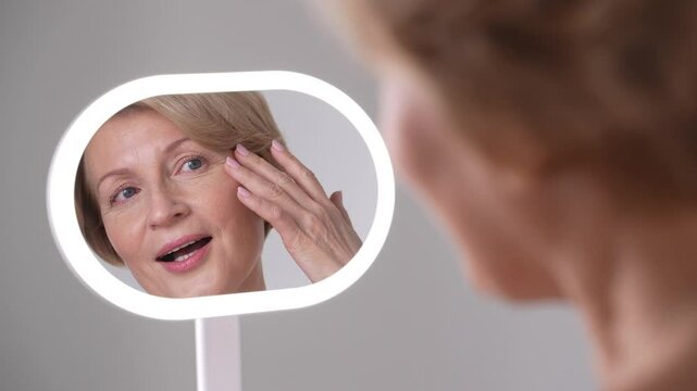 Middle-aged beautiful woman takes a moment to examine her skin closely. The beauty of aging and the journey of selflove