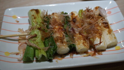 Japanese Grilled Green Onion Skewer with Bonito Flakes on a Plate