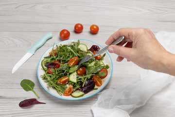 Vegetable salad of tomatoes, cucumbers, greens on the plate with olive oil.