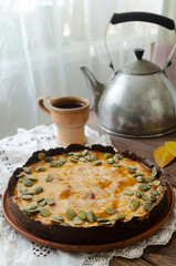Orange pumpkin pie with dried seeds on a ceramic plate with a white napkin on a wooden table. Rustic style. Autumn mood. Tea time concept. Top view. Vertical orientation.