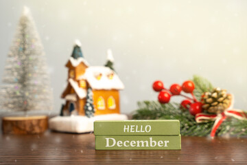 Hello December blocks against the background of a Christmas tree and a house with snow. Concept of the beginning of a new winter season