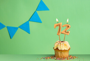 Birthday card with number 72 candle - Cupcake on a green background with blue pennants.