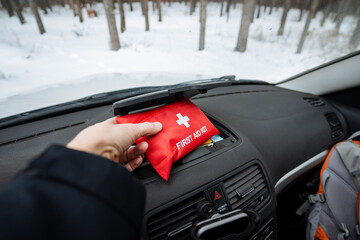 Fototapeta premium In the vehicle, a person is holding onto a first aid kit that is conveniently placed in their car, ensuring they are prepared for any emergency situations that may arise on the road