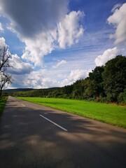 Fototapeta premium A tranquil countryside road bordered by lush greenery and a vibrant sky during the afternoon