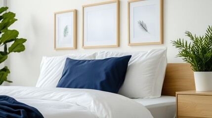 Fototapeta premium A cozy, modern bedroom featuring a blue pillow on a neatly made bed, framed botanical artwork, white bedding, and green plants, creating a serene atmosphere.