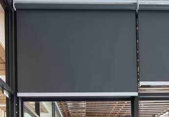 A black rolling curtain is hanging on a window.