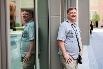 Adult blond man in short sleeve shirt street of a big city.