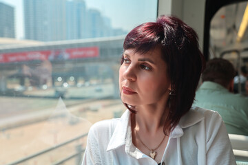 A woman aged 40-44 rides the subway to work, sitting near window.