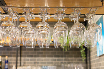 A row of clear glasses hanging from a rack