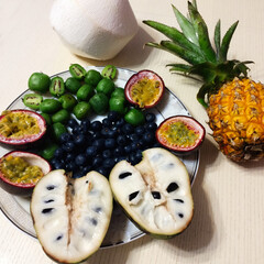 Assortment of fresh exotic fruits on a plate next to a pineapple