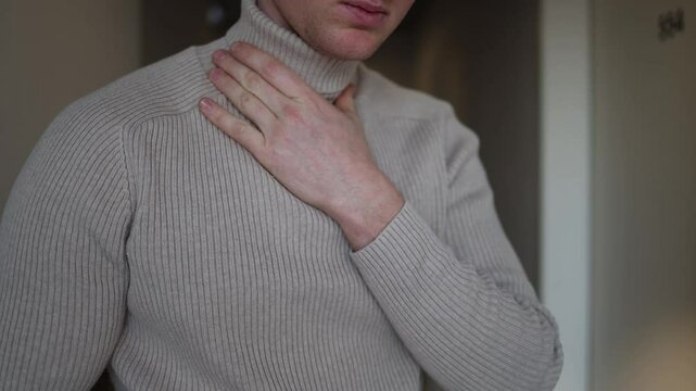 A man holds his hands around his throat, indicating discomfort or a sore throat. This image effectively conveys themes of throat pain, respiratory issues, or health concerns, suitable for medical or w
