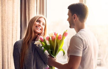 Romantic moment. Young man giving flowers to his girlfriend on special day