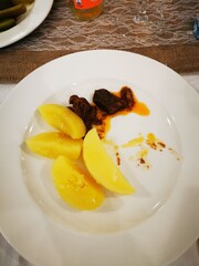 A plate featuring tender meat with a spicy sauce accompanied by sweet potatoes, served during a casual dining experience