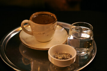 a tray with a cup of coffee, water and sweets. Turkish breakfast in the cafe