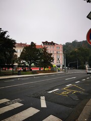 Urban street view featuring a quiet road, residential buildings, and autumn foliage in the early morning