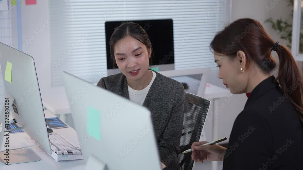 Poster businesswomen discussing work together at an office desk, collaborating in front of a computer durin