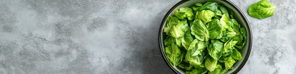 Freshly prepared lettuce in a black bowl on a textured gray surface ready for a healthy meal or salad. Generative AI