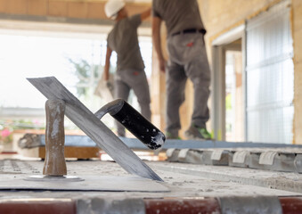 Craftsmen in grey clothes working inside a room standing on scaffoldings during construction