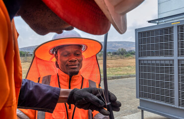 african workers fixing air conditioning, hvac outdoors unit industrial