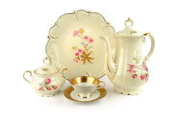 Vintage tea cup, sugar bowl, coffee pot and dish isolated on white.