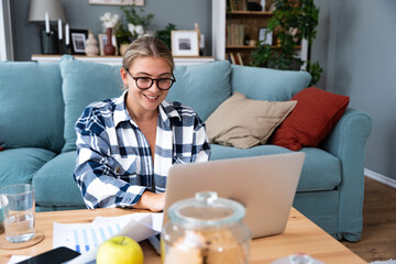 Smiling young woman working at home. Successful professional occupation female work on laptop...
