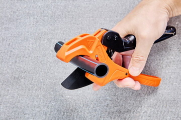 Cutter scissors for plastic pipes are equipped with ratchet mechanism, hand holds plumber tool on...
